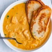 Creamy yellow butternut squash soup with chunks of butternut squash and sourdough toast.