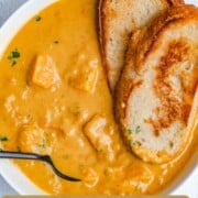 Creamy yellow butternut squash soup with chunks of butternut squash and sourdough toast.