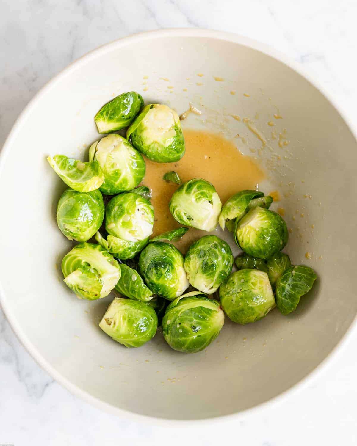 Trimmed Brussels sprouts in a bowl with dressing.