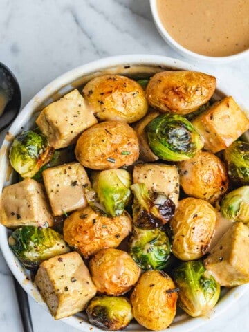 Roasted tofu, Brussels, and potatoes in a bowl with Dijon dressing.