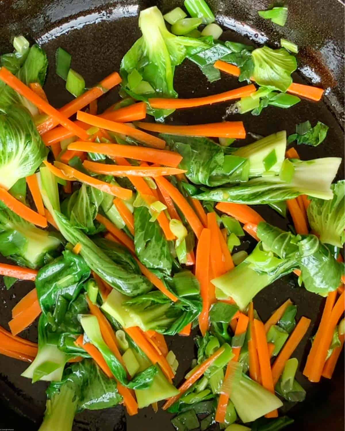 Stir-fry baby bok choy, carrots, and green onions in a large skillet.
