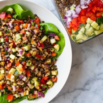 Lentil Vegan Salad with vegan lemony olive oil dressing, cucumber, red bell pepper, red onion, high-protein French lentils, farro, peanuts, and parsley.