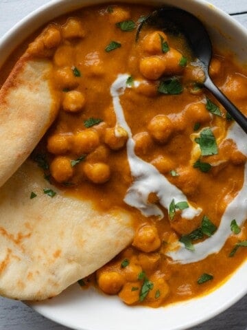 Pantry Chickpea Pumpkin Curry with naan in a white bowl.