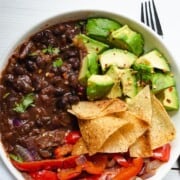 Spiced Tofu & Black Bean Vegan Chili with sautéed bell peppers and avocado in a bowl.