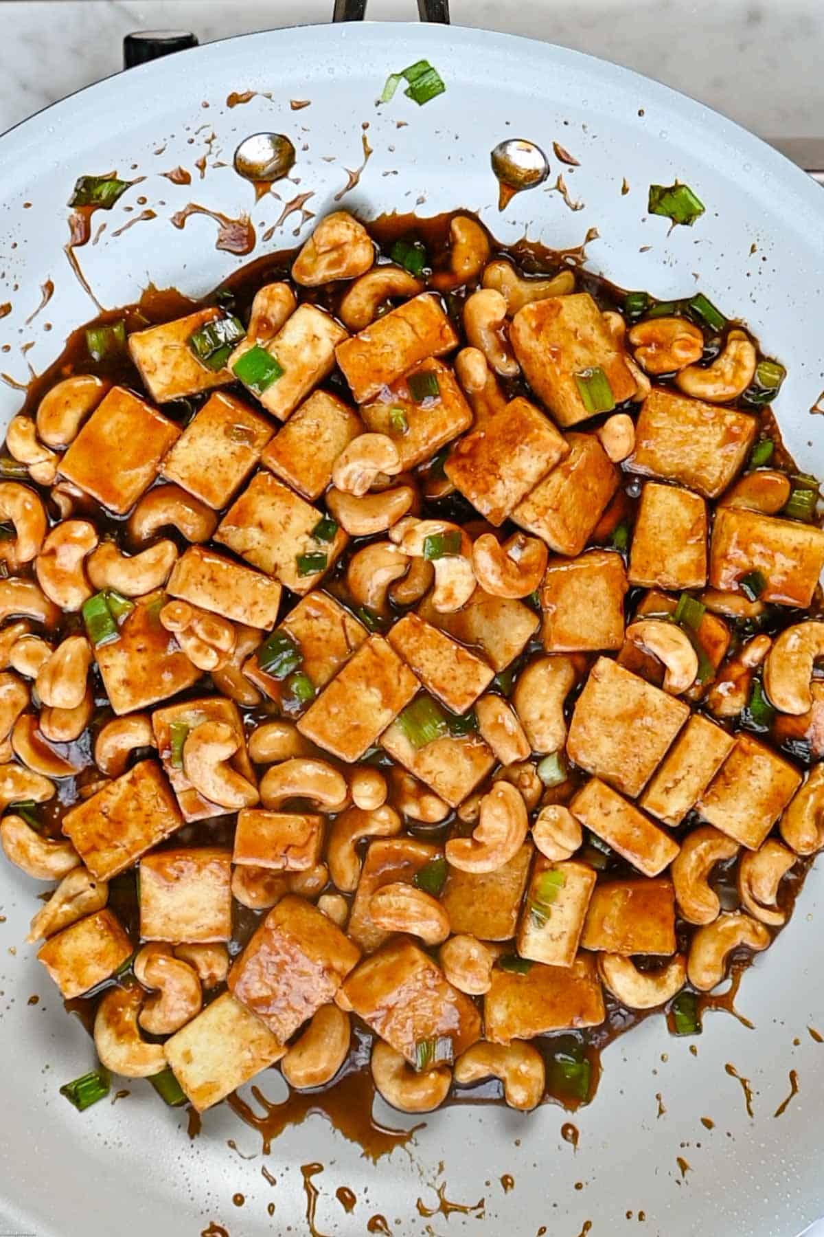 Tofu, green onions, cashews, and sauce in a large skillet.