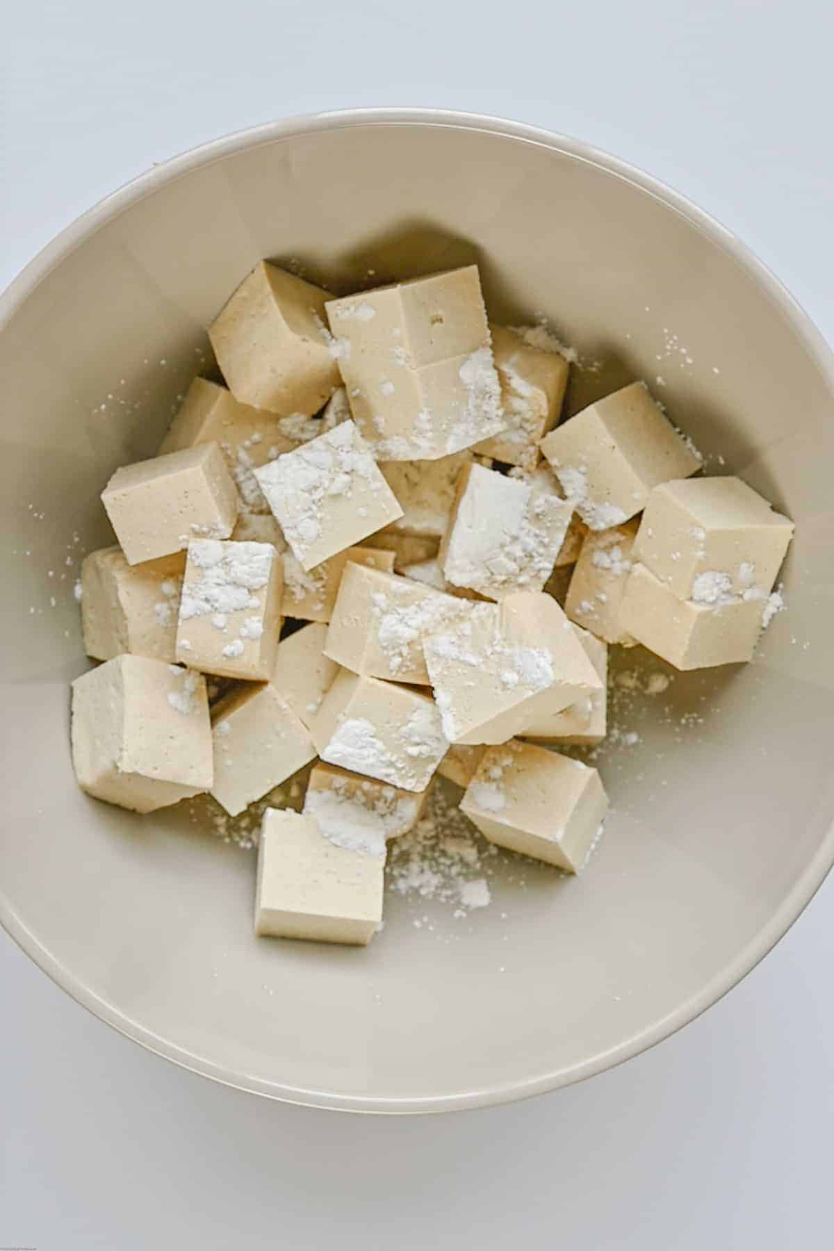 Cubed tofu in a bowl with cornstarch.