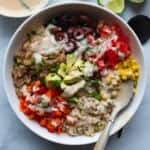 High-Protein Refried Bean Veggie Bowl with fresh lime and creamy dairy-free vegan ranch dressing.