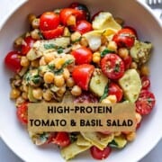 High-Protein Tomato & Basil Salad: Halved grape tomatoes, avocado chunks, fresh mint and basil, grain mustard lemon dressing, artichoke hearts, chopped pistachios, and chickpeas mixed in a bowl.