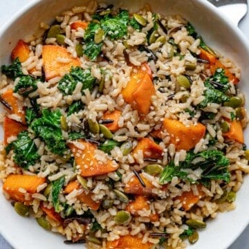 Kale & Sweet Potato Wild Rice Salad in a white bowl with a silver fork.