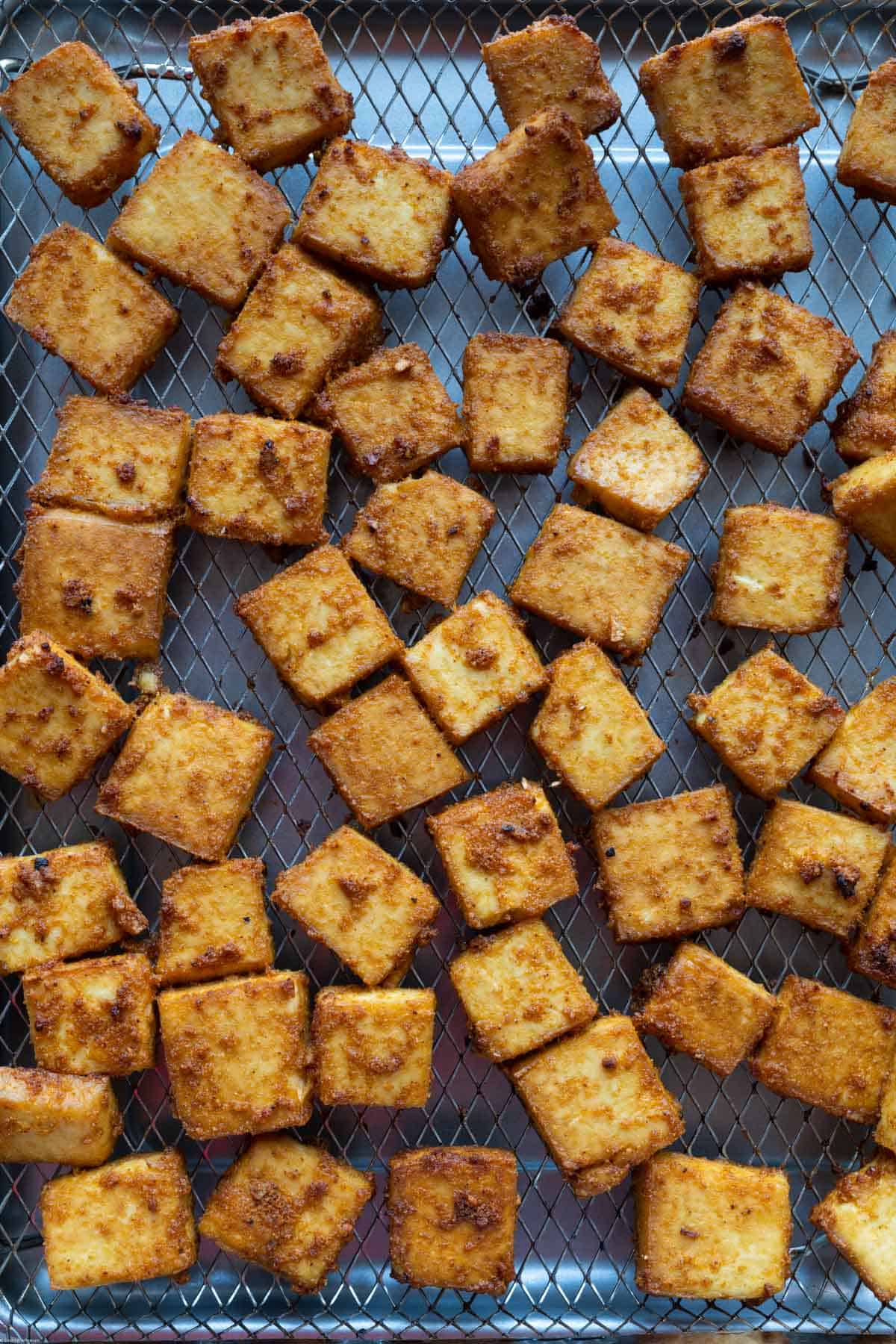 Crispy air fried tofu cubes on a cooking tray.