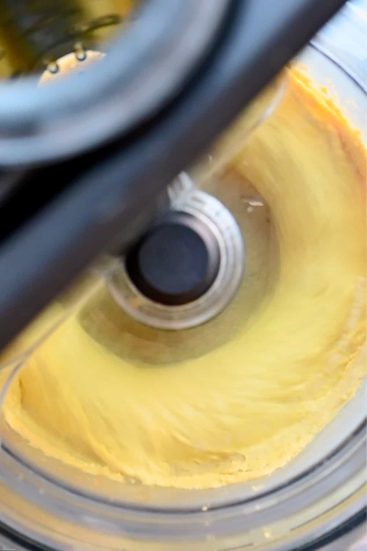 Bright yellow red lentil dip blending in a food processor.
