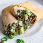 One wholewheat wrap with lentil salad and hummus, cut into two.