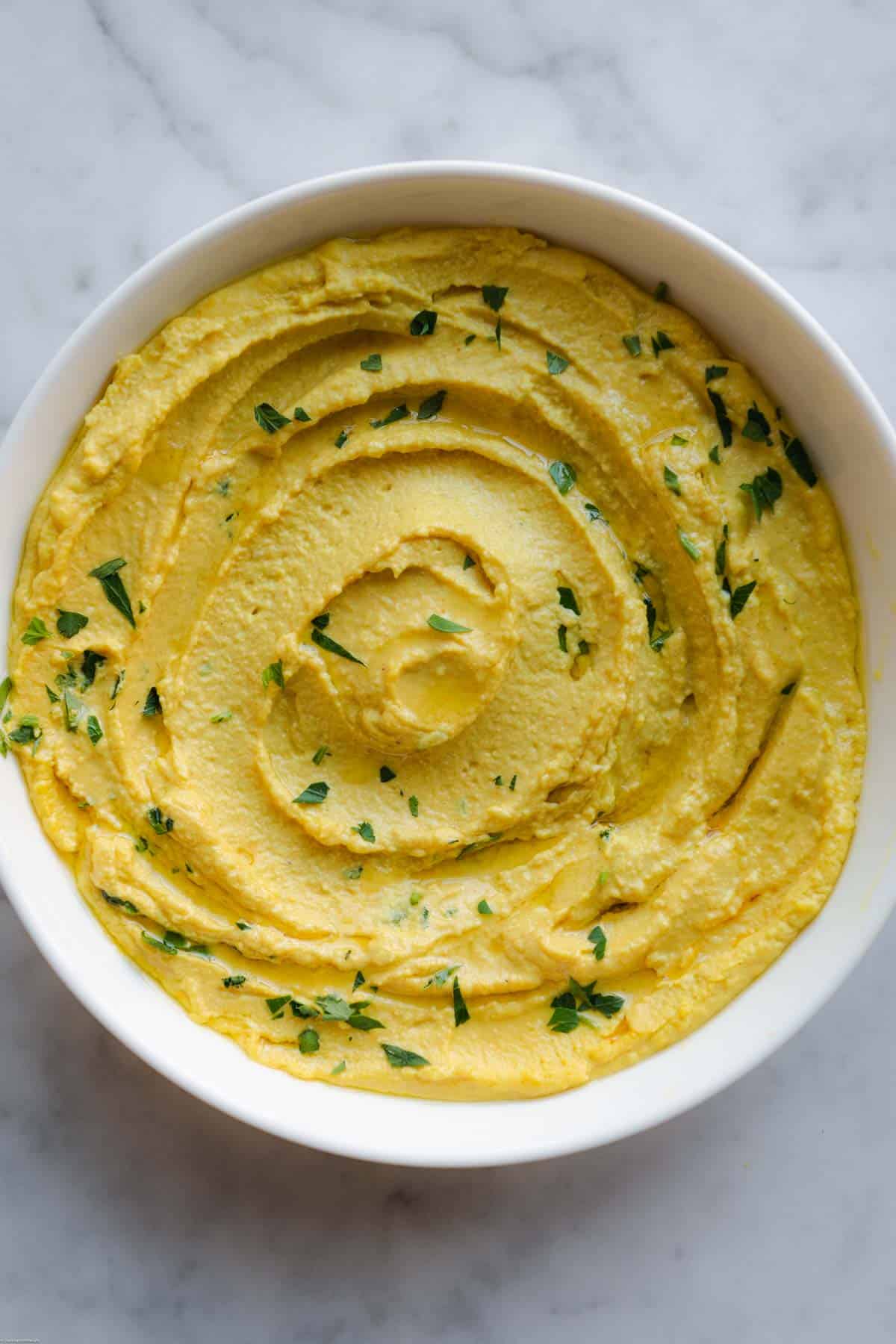 High-Protein Red Lentil Dip in a white bowl with chopped parsley.