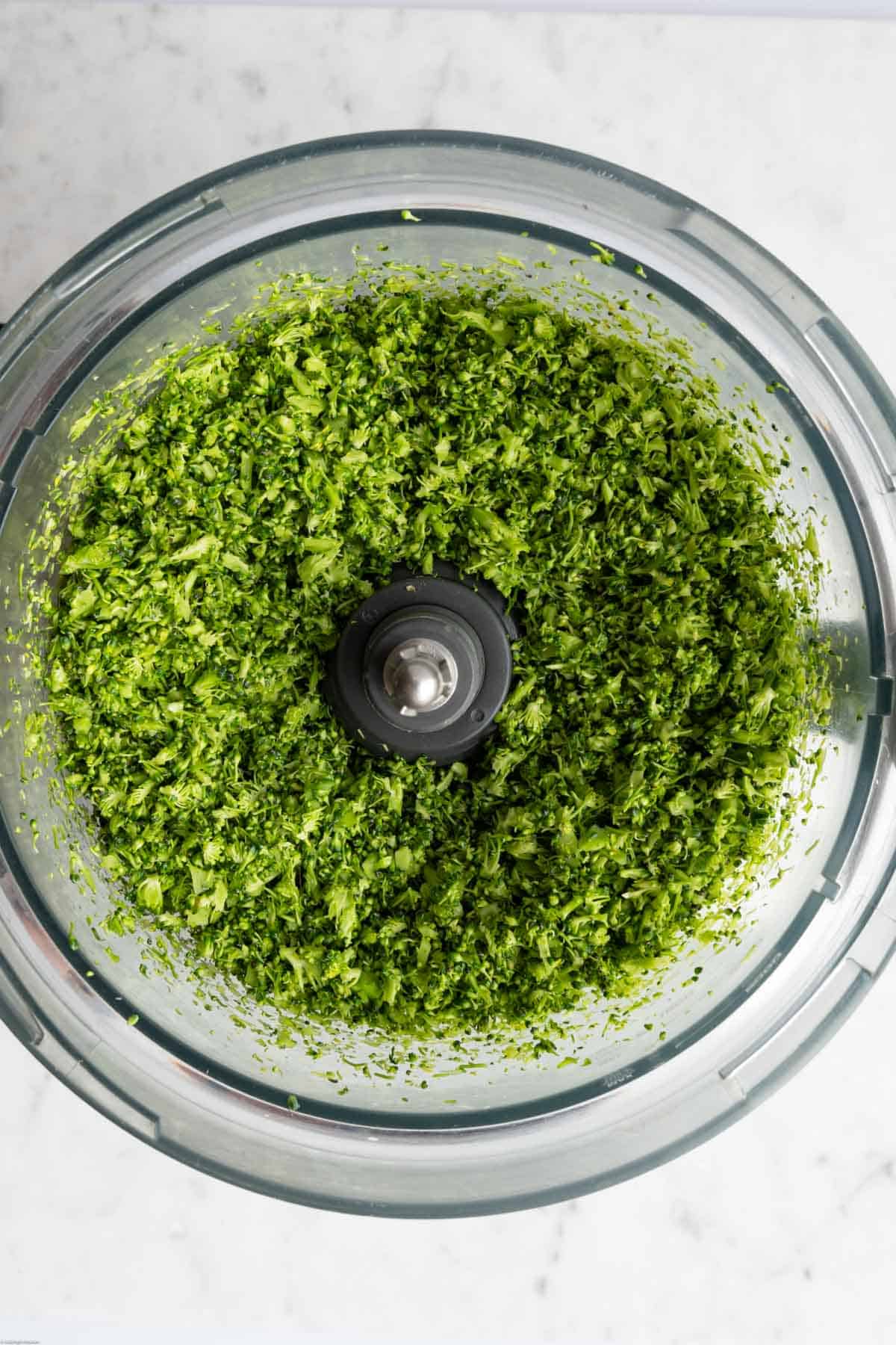 Riced broccoli is the canister of a food processor.