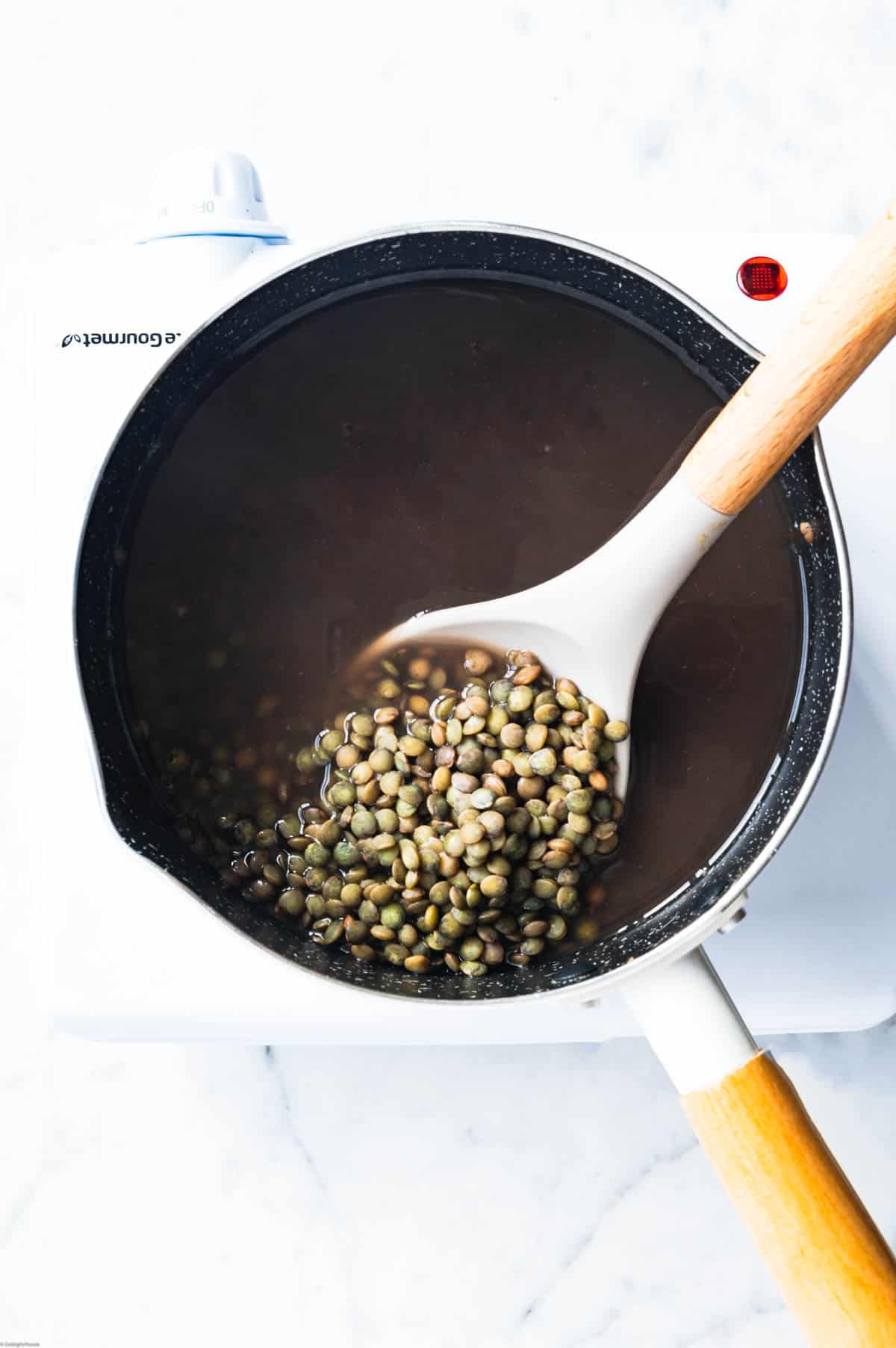 French lentils cooking in a white saucepan.