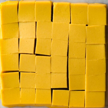 Cubed yellow chickpea tofu on a white marble board.