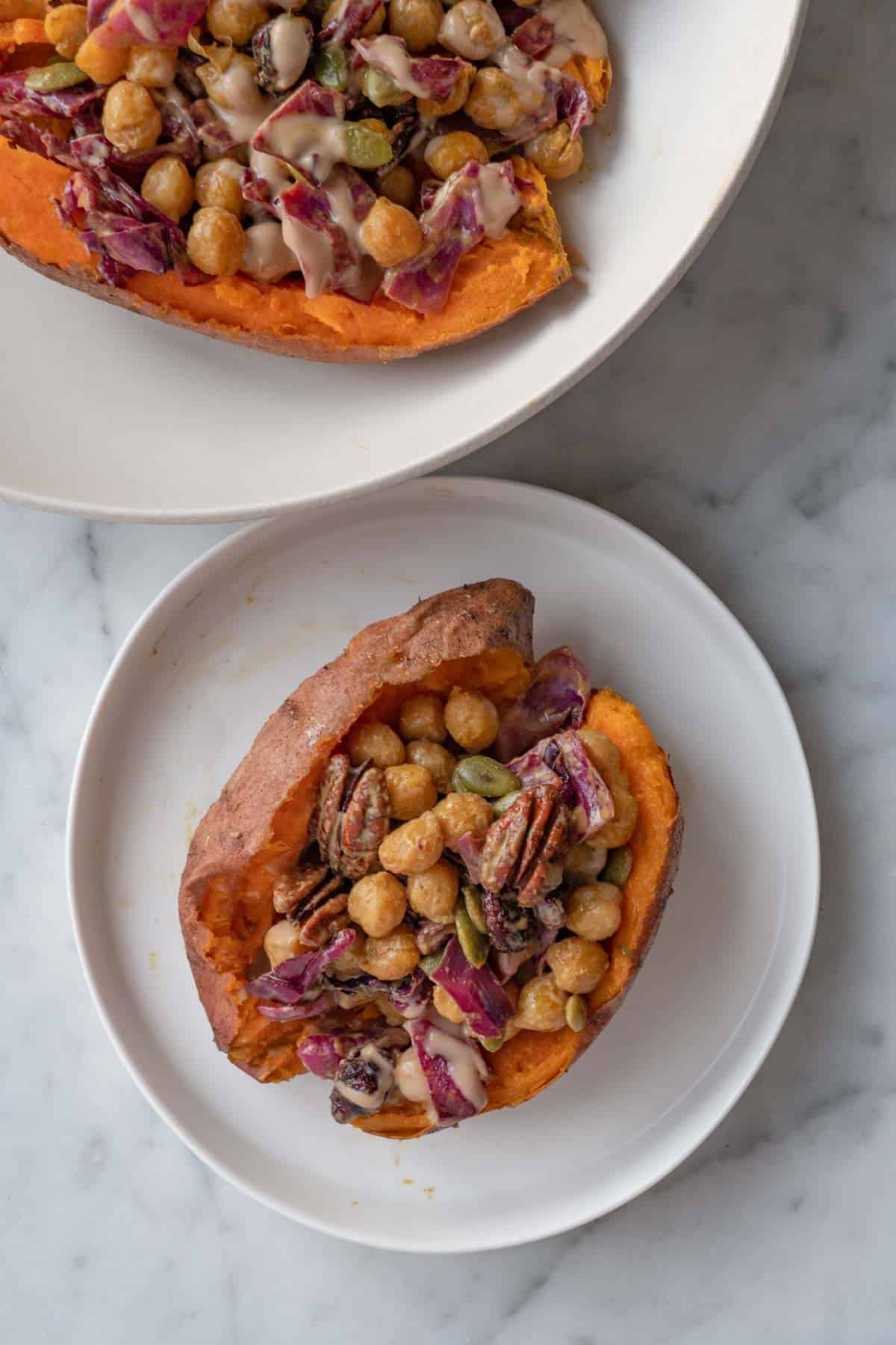 Sliced orange sweet potato stuffed with roasted chickpeas, red cabbage, dried cranberries, pecans, pepitas, and creamy dressing.
