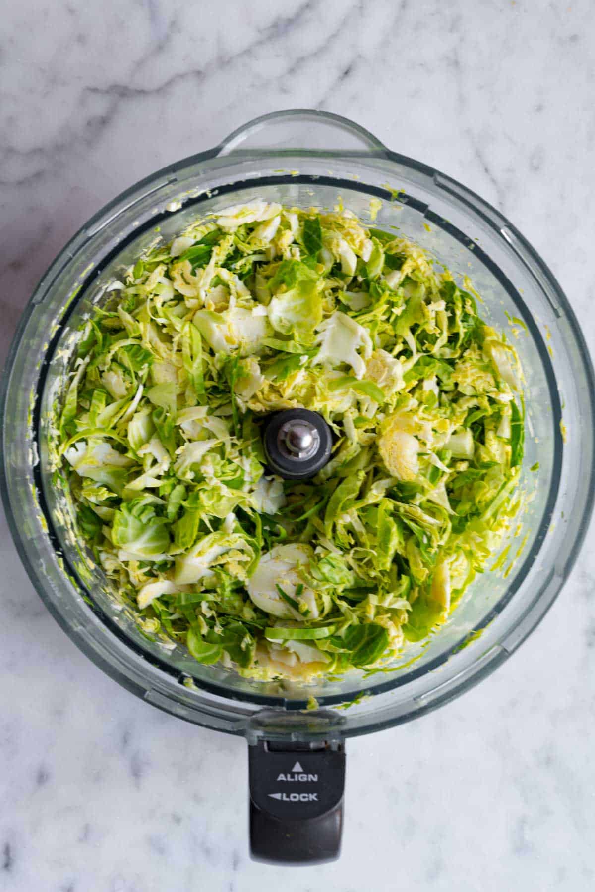 Shaved Brussels sprouts in canister of a food processor.