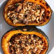 Roasted kabocha squash halves, stuffed with tofu taco meat and rice in a white bowl.
