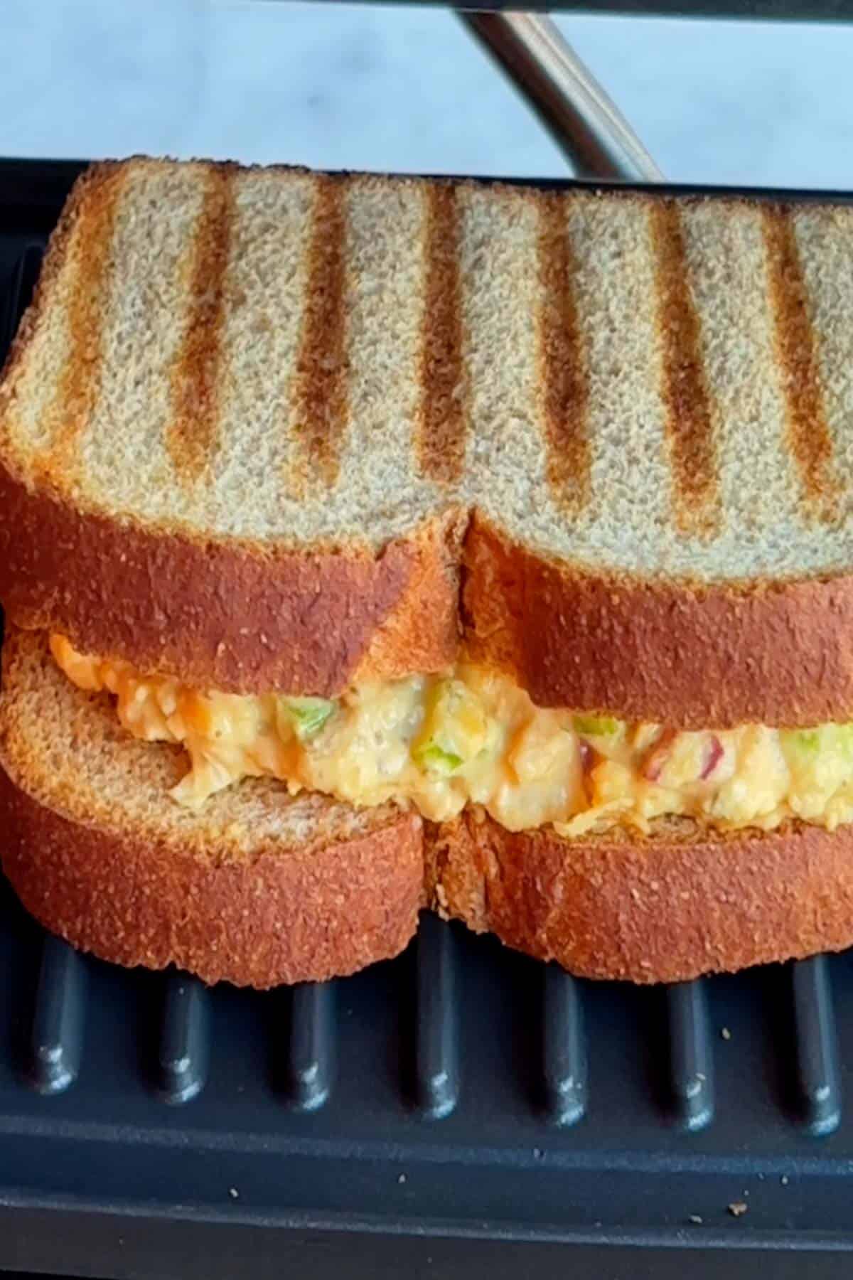Vegan tuna sandwich with grilled whole wheat bread in a sandwich press.