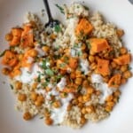 Sweet potato, roasted chickpeas, quinoa, white creamy dressing, and a chopped parsley garnish.