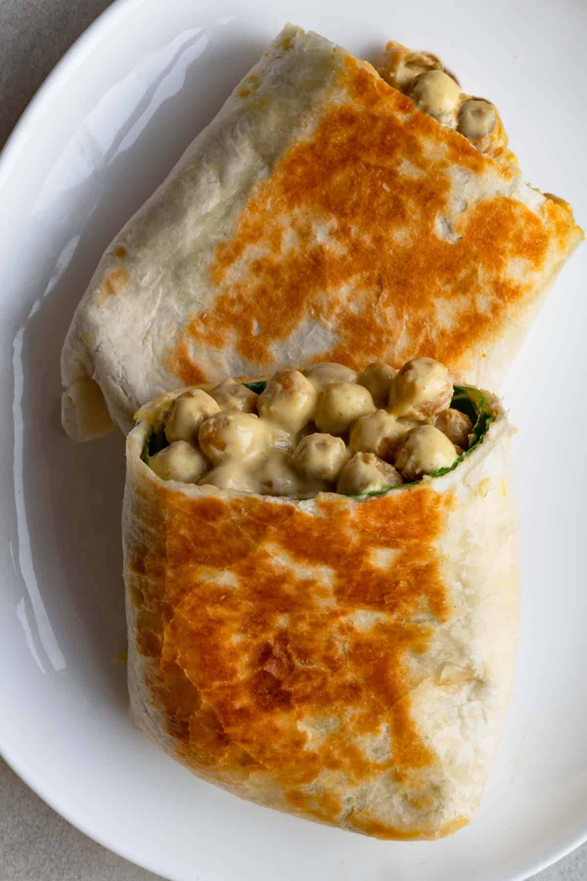 Crispy wrap cut in half with a creamy chickpea and collard green filling.