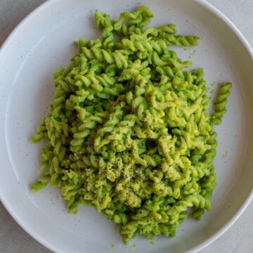 Pasta with creamy green peas sauce on a white plate.