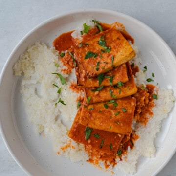 Thai red curry with baked tofu on white rice in a white dish, garnished with chopped cilantro.
