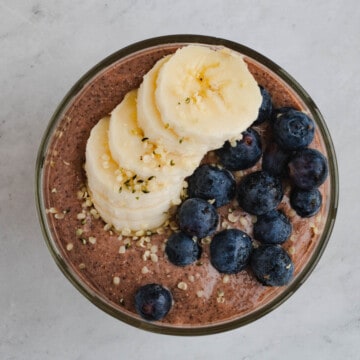 Blended chocolate chia pudding in a glass jar topped with blueberries and banana.