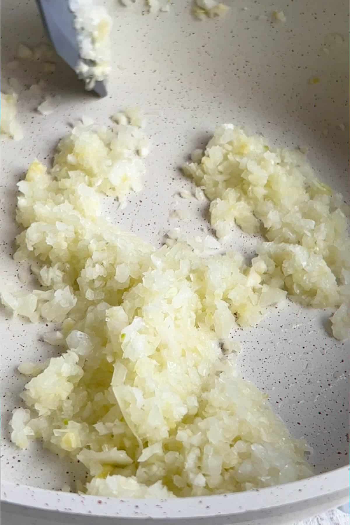 Cooked onion in a white skillet.
