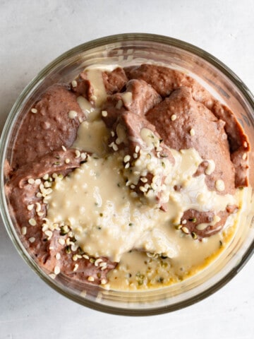 Edible cookie dough (chocolate) in a glass container, topped with tahini and hemp seeds.