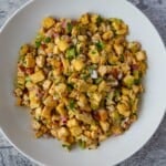 Marinated tofu salad with cubed baked tofu, chopped red onion, parsley, and celery in a white bowl on a gray backdrop.