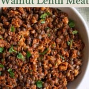 Walnut meat with lentils in a white bowl topped with chopped cilantro.