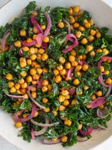 Best kale and crispy chickpea salad with easy lemon vinaigrette in a white bowl topped with croutons.