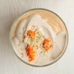 Blended chia pudding in a bowl topped with vegan nut cream, grated carrots, and hemp seeds.