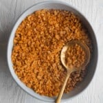 Golden brown gluten-free chickpea breadcrumbs in a bowl with a spoon.