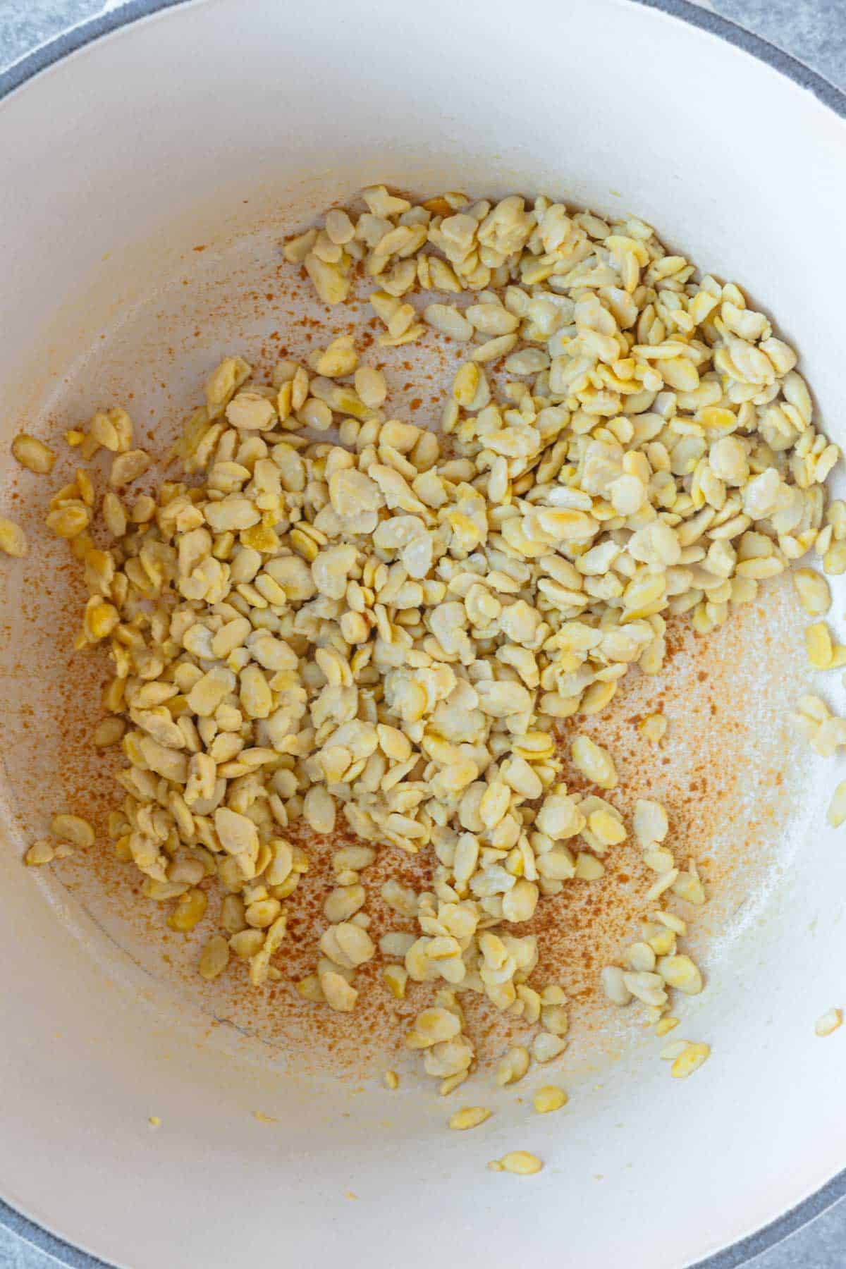 White crumbles cooking in a white saucepan.