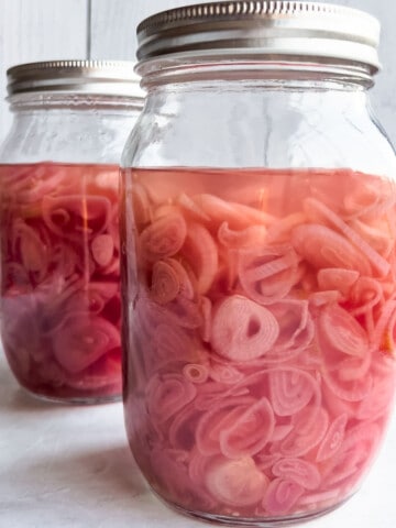 Two mason jars with homemade Easy Pickled Shallots.