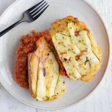Vegan zucchini lasagna sliced in two on a white plate.