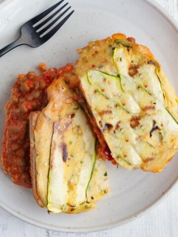 Vegan zucchini lasagna sliced in two on a white plate.