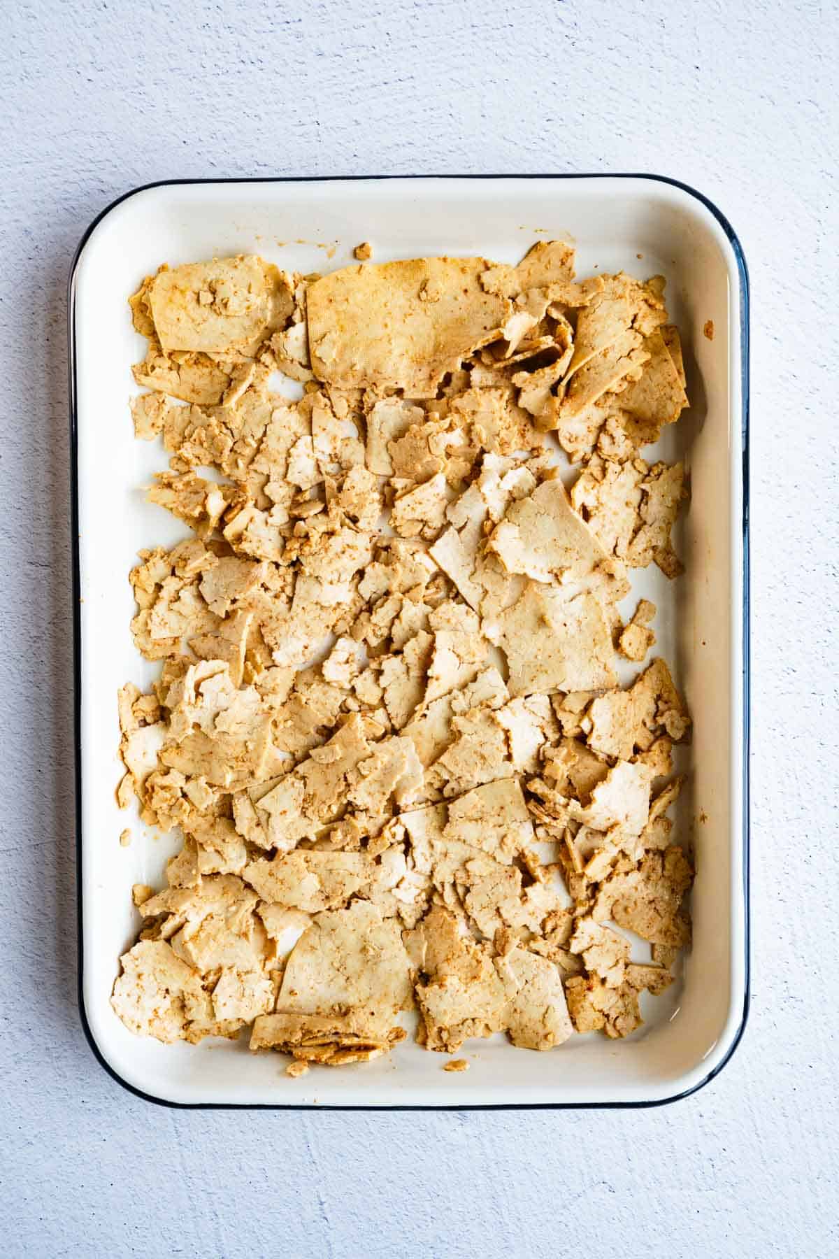 Grated marinated tofu on a white baking sheet.