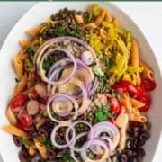 Lentil pasta salad with green lentils, olives, red onion, red lentil pasta, pepperoncini, parsley and tahini dressing.