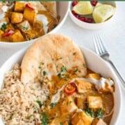 Two white bowls with vegan butter chicken made from tofu and served with rice and naan.