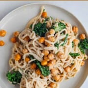 Creamy pasta with tahini, chickpeas, and broccoli on a white plate.