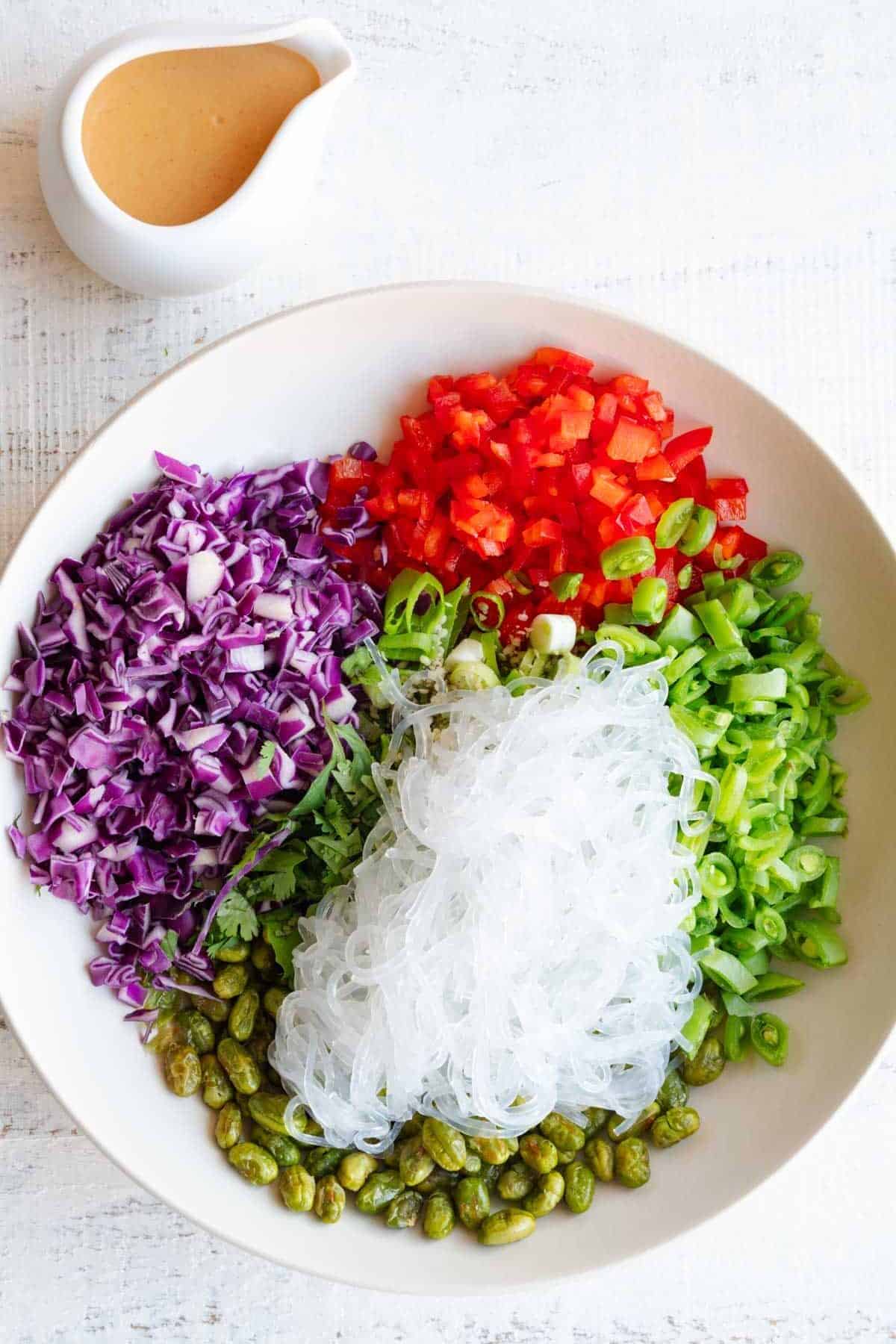 Thai Salad Dressing in a white pouring bowl with a bowl of Thai Crunch Salad.
