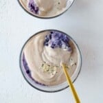 Two glass containers with berry chia pudding and walnut cream with a golden spoon.