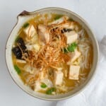 Miso soup with noodles, mushrooms, tofu, nori seaweed, and green onion.