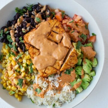 Baja bowl with rice, avocado, corn, tomatoes, black beans, and tofu steak with Baja sauce.