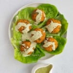 Vegan Turkish lentil balls (Mercimek Köfte) on lettuce leaves with green capsicum chutney.