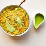 High-protein vegan risotto in a white bowl with a side of green miso sauce.